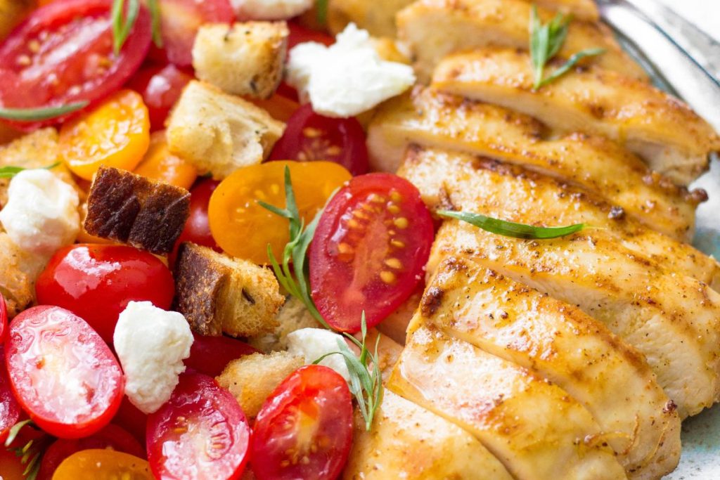 Grilled chicken and tomatoes on a plate.